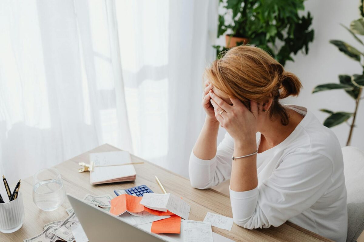 Woman stressed over financial receipts at a desk, dealing with expenses and calculations. HMRC Self Assessment Deductible Expenses